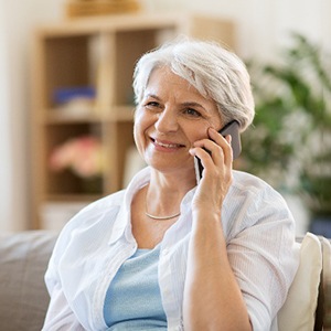 Senior woman smiling while talking on phone at home