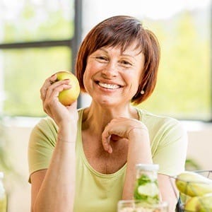 Smiling older woman holding an apple