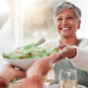 Middle-aged woman smiling and eating a salad with friends
