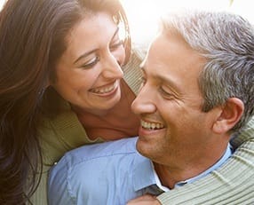 Smiling man and woman holding each other outdoors