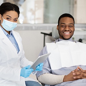 Dentist and patient smiling while sitting in treatment room