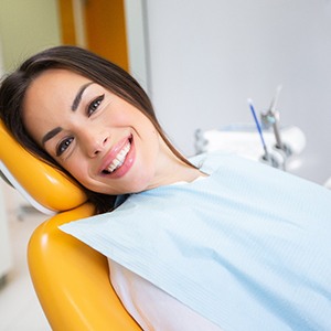 Female patient leaning back in dental chair and smiling