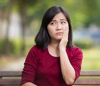 Woman holding cheek outdoors