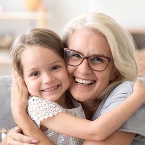 older woman smiling and hugging young girl