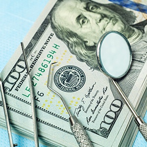 stack of money with dental tools on table