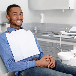 Man sitting in dental chair smiling with hands folded
