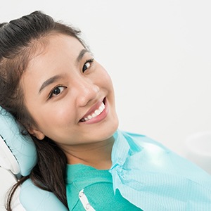 Woman sitting back in dental chair and smiling