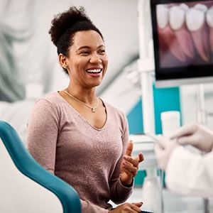 Woman smiling while talking to cosmetic dentist about veneers