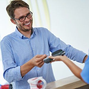 Man smiling while paying for dental care with credit card