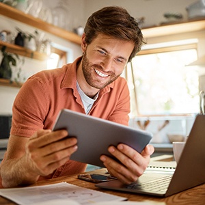 a person smiling while looking at a tablet