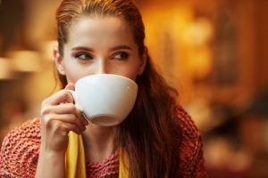 A woman drinking out of a mug.