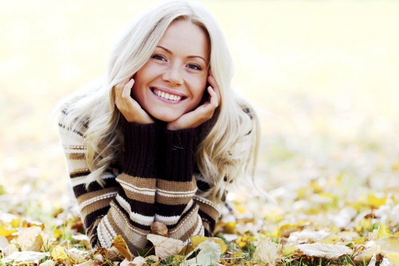 a young woman lying in the leaves and smiling