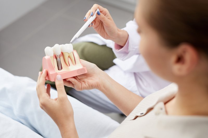 a patient looking at a mold with a dental implant