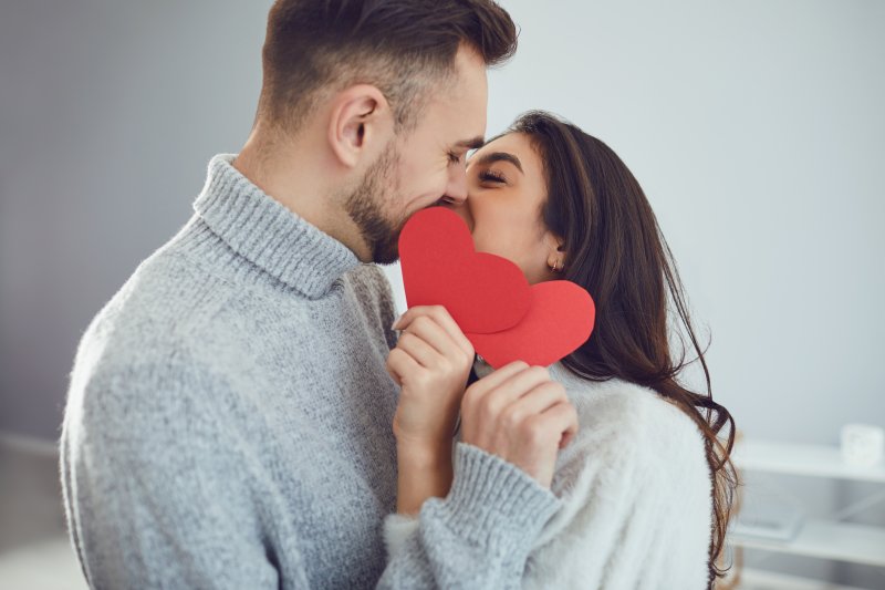 a couple kissing with two hearts in front of their mouths