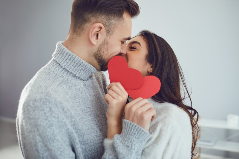 a couple kissing with two hearts in front of their mouths 