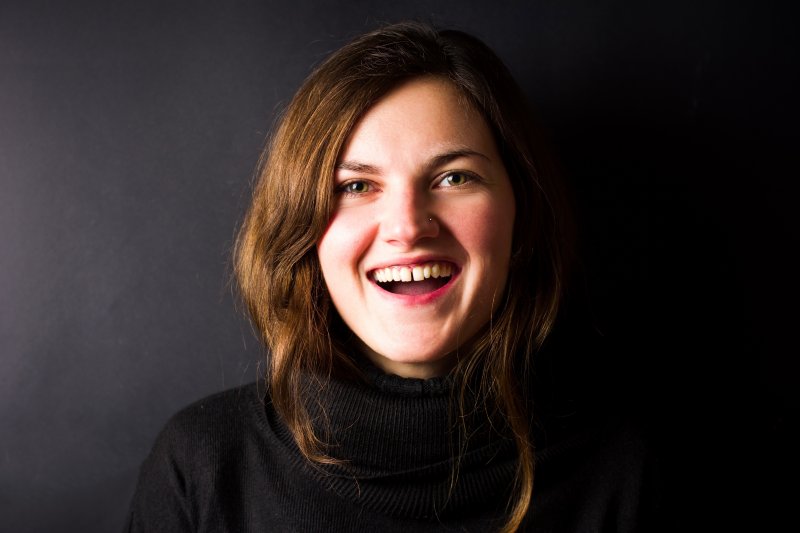 a young woman wearing a black sweater smiling with a gap between her two front teeth