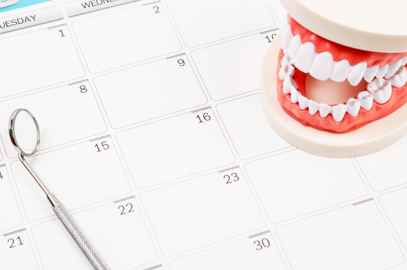 a calendar for a dentist in North Naples with a mouth mold and dental mirror instrument laying on top 