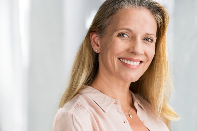 an older woman shows off her smile after replacing a missing back tooth in North Naples