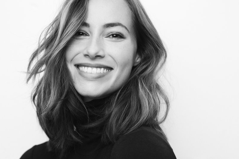 a young woman wearing a black sweater and smiling after choosing between veneers or crowns in North Naples