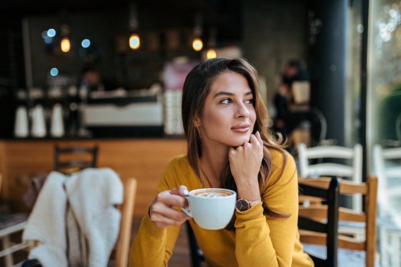 young woman drinking coffee with Invisalign