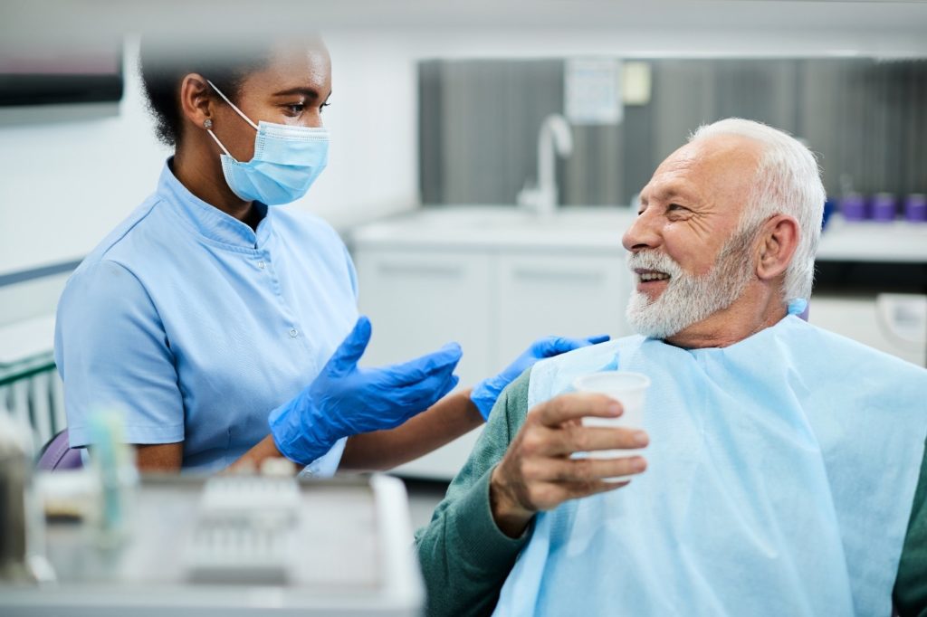 Female dentist talking to smiling patient about dental implants