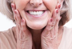 a woman smiling and showing her healthy dentures