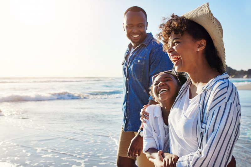 Patient smiling with family on beach after cosmetic dentistry