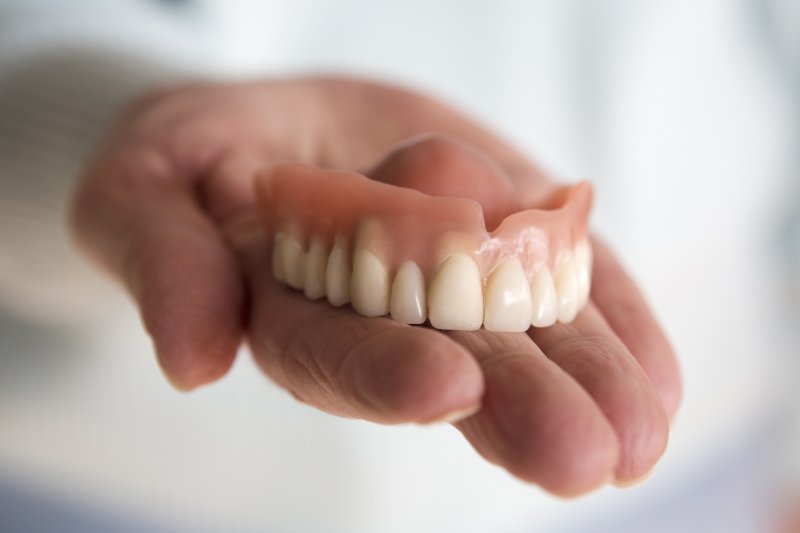 person holding a full upper denture 