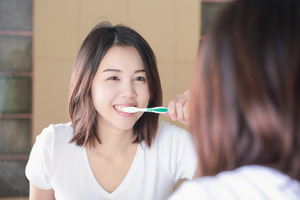 Woman brushing her teeth in the mirror
