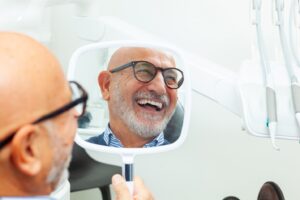 Man with glasses smiling with dental implants