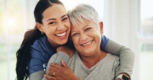 Daughter hugging and smiling alongside her mother